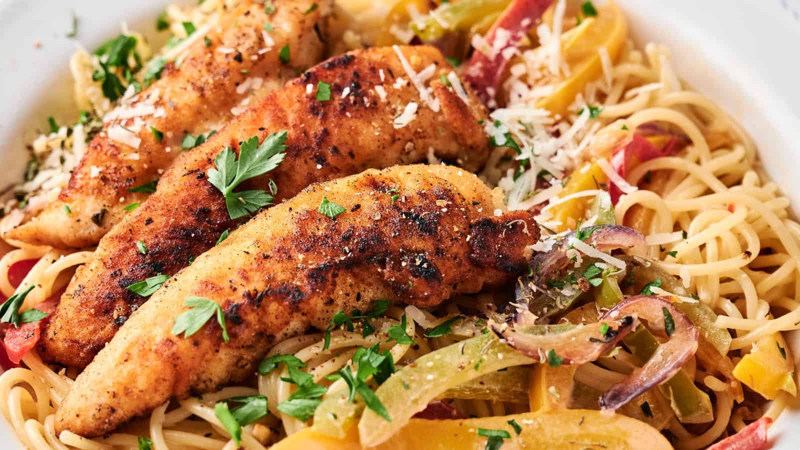 A plate of spaghetti topped with grilled chicken strips and garnished with chopped parsley, bell peppers, and shredded cheese.