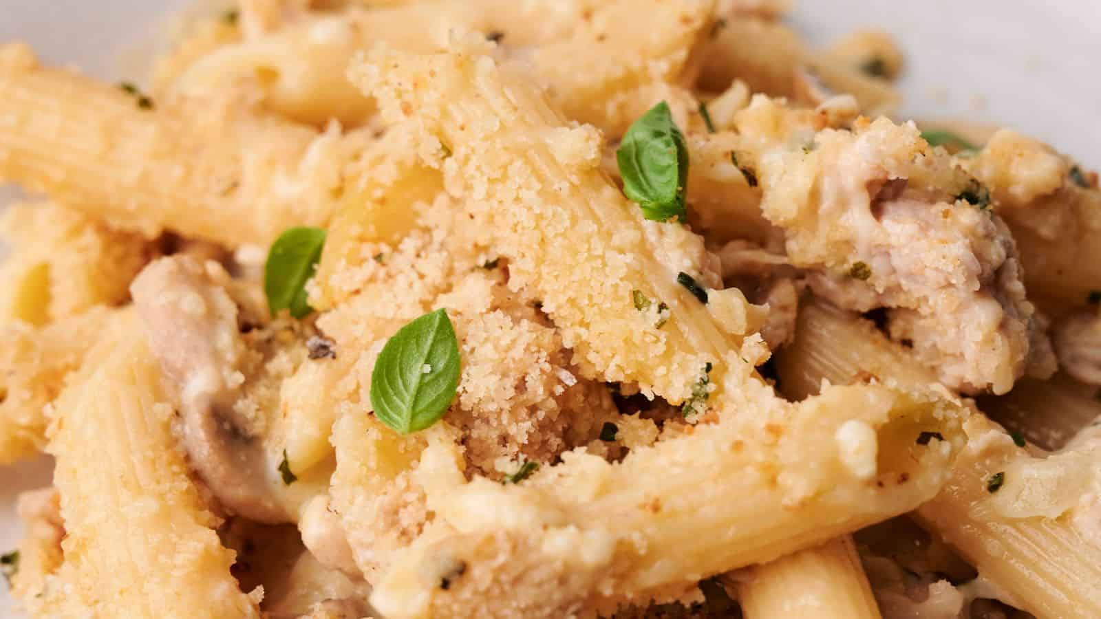 Close-up of a plate of creamy turkey casserole topped with bread crumbs and garnished with fresh basil leaves, reminiscent of a comforting turkey casserole.