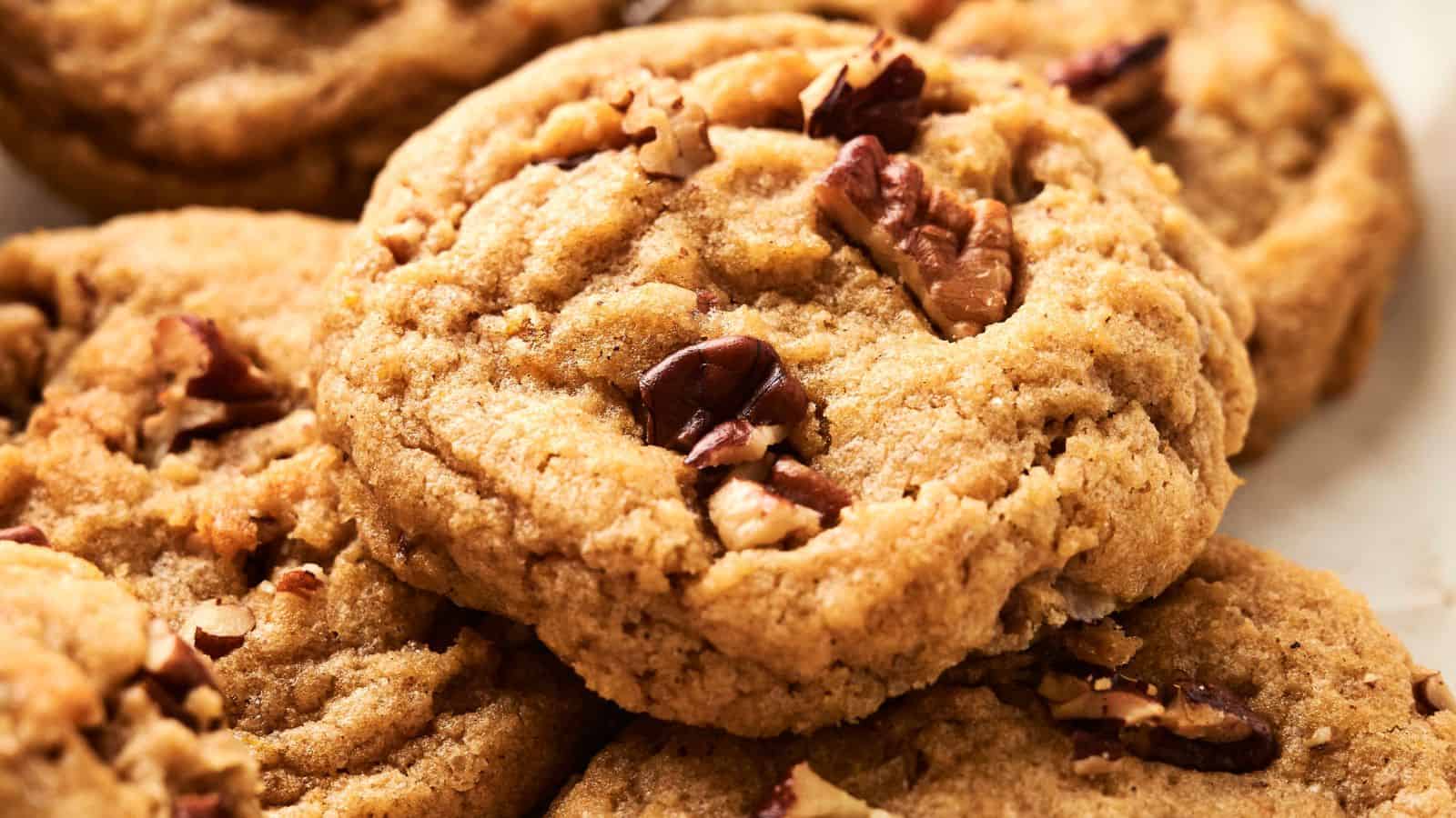 Close-up of freshly baked cookies with nuts on top, arranged closely together.